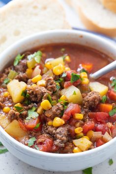 a white bowl filled with meat and vegetables next to some pita bread on the side