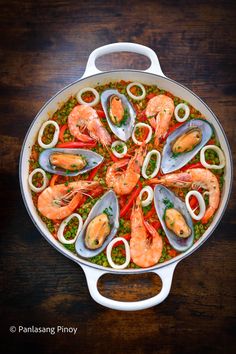 a pan filled with seafood and vegetables on top of a wooden table