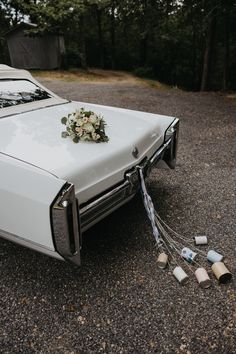 a wedding car with flowers on the hood and ribbons tied to it's side