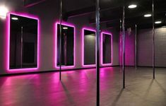 an empty room with mirrors and lights on the walls in front of them is lit up by purple lighting