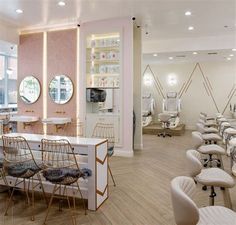 the interior of a nail salon with chairs and mirrors on the wall, lights in the ceiling