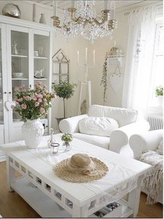 a living room filled with furniture and a chandelier hanging from the ceiling over a white coffee table