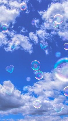 many soap bubbles floating in the air on a sunny day with blue sky and clouds