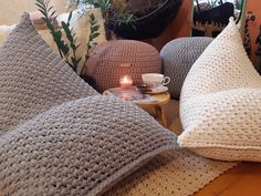 crocheted pillows on a table with a candle and potted plant in the background