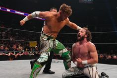 two men wrestling in an arena with people watching