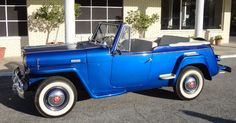 an old blue car parked in front of a building