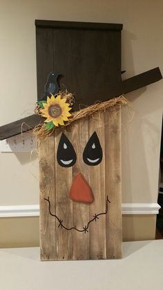 a wooden block with a scarecrow face painted on it and a sunflower sticking out of the top