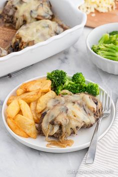 a white plate topped with meat covered in gravy next to french fries and broccoli