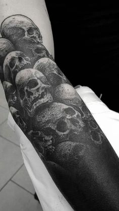 a man with a black and white tattoo on his arm that has skulls all over it