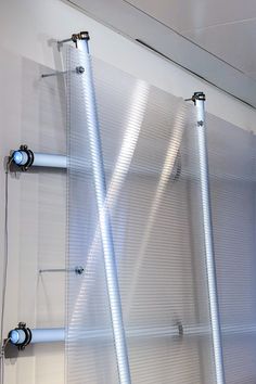 three metal tubes are attached to the wall in front of a white background with light coming through them