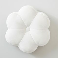 a white flower shaped pillow sitting on top of a table