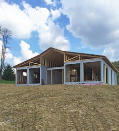 a house under construction on top of a hill with blue sky and clouds in the background