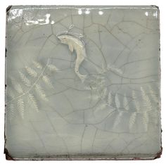 a white tile with some plants and leaves in the middle, on top of it