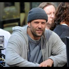 a man with a beanie sitting in front of a camera on the set of a movie