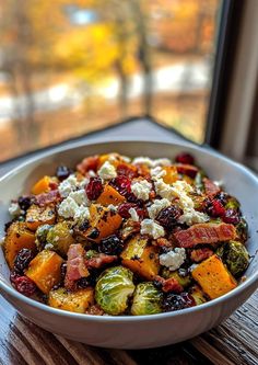 a white bowl filled with brussel sprouts, bacon and other vegetables