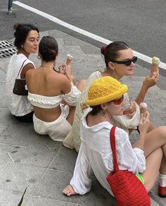 three women sitting on the ground eating ice cream