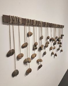 a group of rocks hanging on a wall next to a white wall with ropes attached