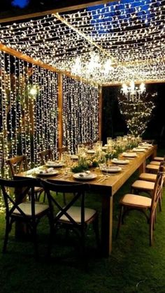 an outdoor dining area with lights strung from the ceiling and table set up for dinner