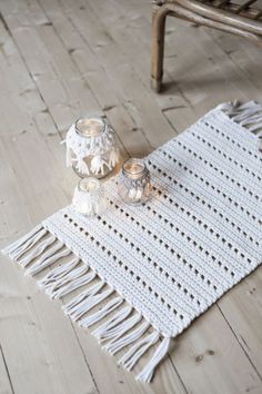 a white table runner sitting on top of a wooden floor next to a candle holder