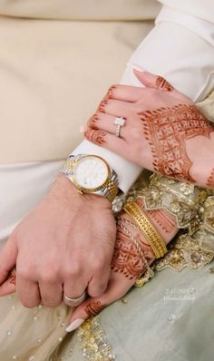 the bride and groom are holding hands with their wedding rings on each hand, both wearing matching bracelets