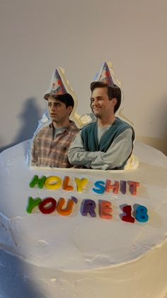 two men sitting on top of a white cake