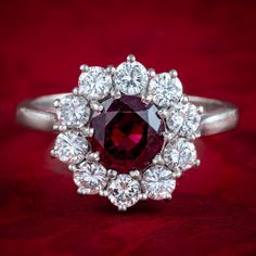 a ring with a large red stone surrounded by smaller white stones on a red background