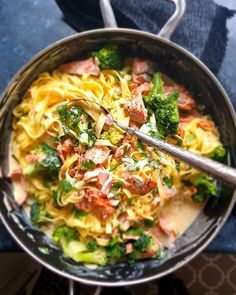 a pan filled with pasta and broccoli on top of a blue table cloth