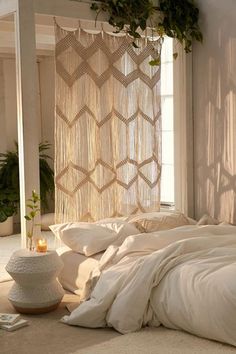 an unmade bed with white sheets and pillows in a room next to a window