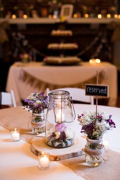 the centerpieces are filled with flowers, candles and small mason jar vases