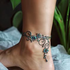 a woman's foot with a blue flower ankle bracelet on top of her leg