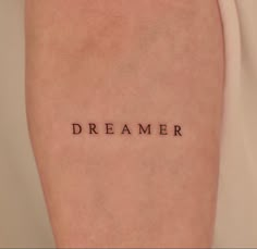 a woman's arm with the word dream written on it in cursive font