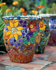 three colorful flower pots sitting on top of a brick floor