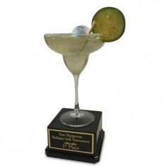 a martini glass with a lime slice in it on top of a black marble base