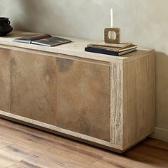 a wooden cabinet sitting on top of a hard wood floor next to a vase and book