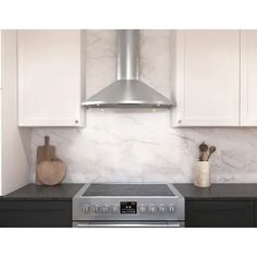 a stove top oven sitting inside of a kitchen next to white cabinets and wooden cutting boards