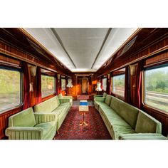 the interior of a train car with green couches and red rugs on the floor