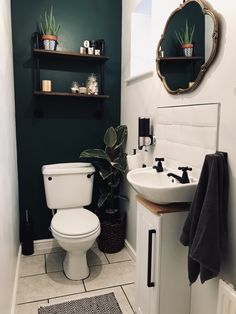 a white toilet sitting next to a sink in a bathroom under a mirror above a wooden shelf