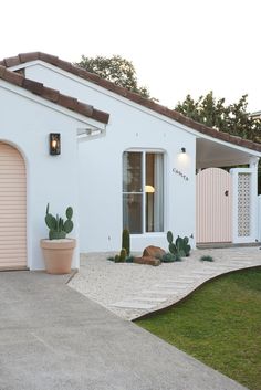 a white house with cactus plants in the front yard