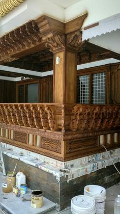 an elaborate wooden structure being worked on in a building under construction with buckets and paint