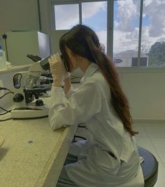 a woman in white lab coat sitting at a counter