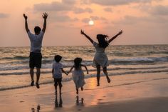 three people jumping in the air at the beach with their hands up to the sky