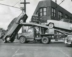 an old black and white photo of a car being transported by a truck with the hood open