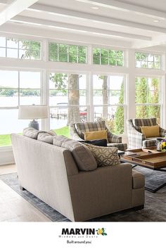 a living room filled with lots of furniture and large windows over the top of it