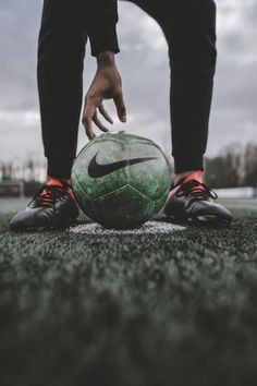 a person standing next to a green soccer ball