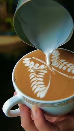 someone is pouring something into a cup that looks like a leaf on the inside of it