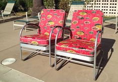 two red chairs sitting next to each other on top of a cement floor covered ground