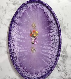 a purple plate with flowers on it sitting on a marble surface