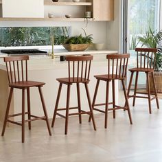 three wooden stools sit in front of a kitchen island