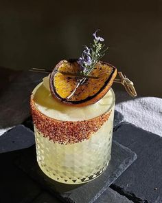 a dessert with orange slices and lavender sprigs on top is sitting on a table