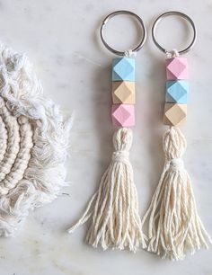 two key chains with tassels on top of a white table next to a rug